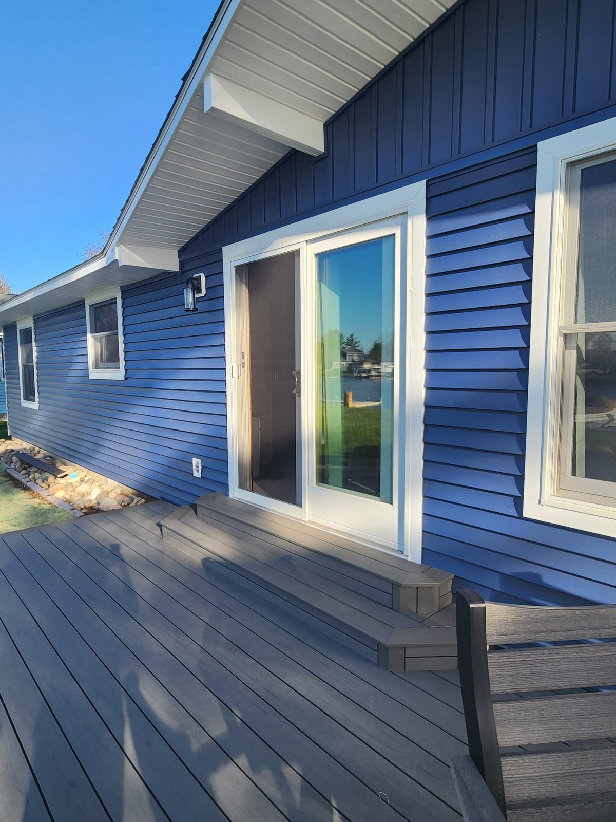 Lakefront up-north cabin with a finished blue exterior and a new composite deck overlooking the water