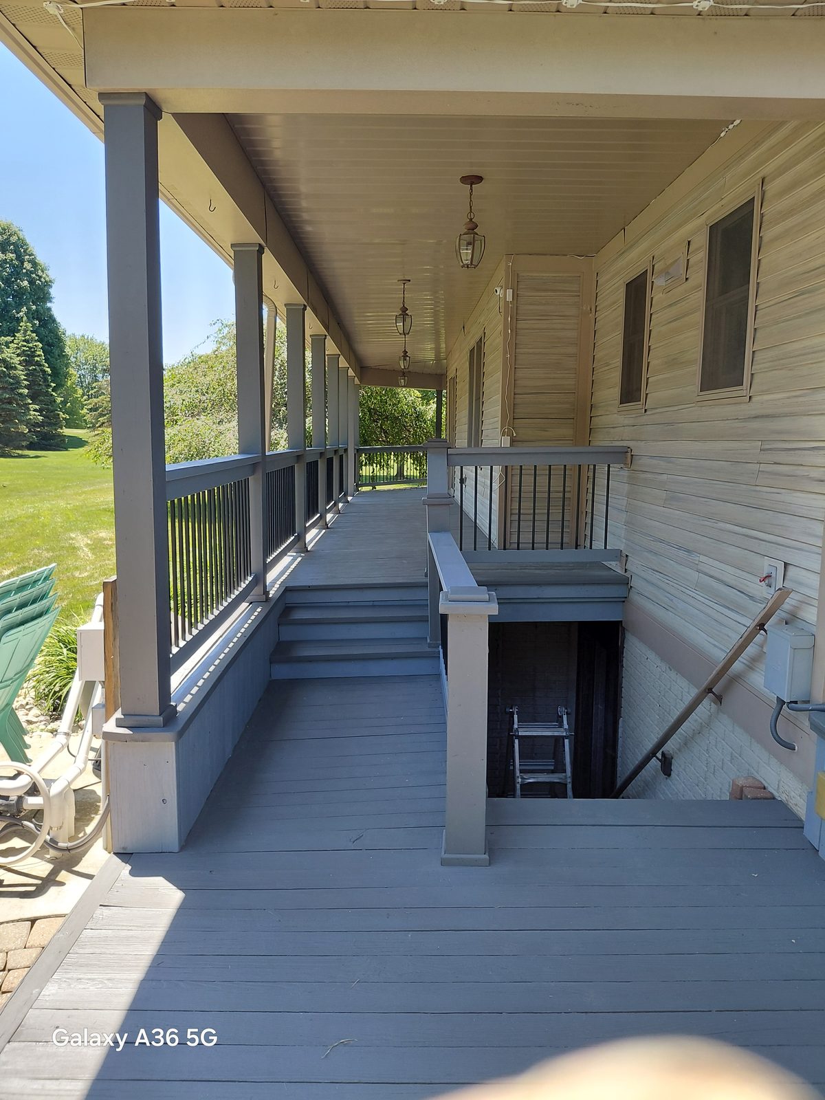 Long covered porch walkway after refinishing with a clean gray painted deck