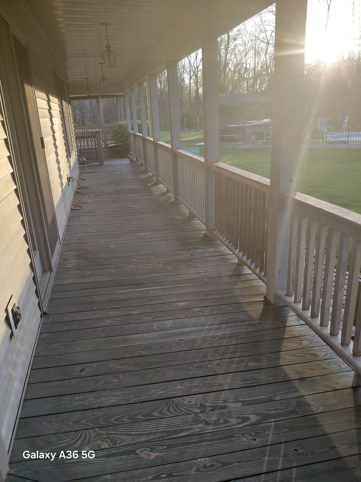 Long covered porch walkway before refinishing, with faded and worn wood decking