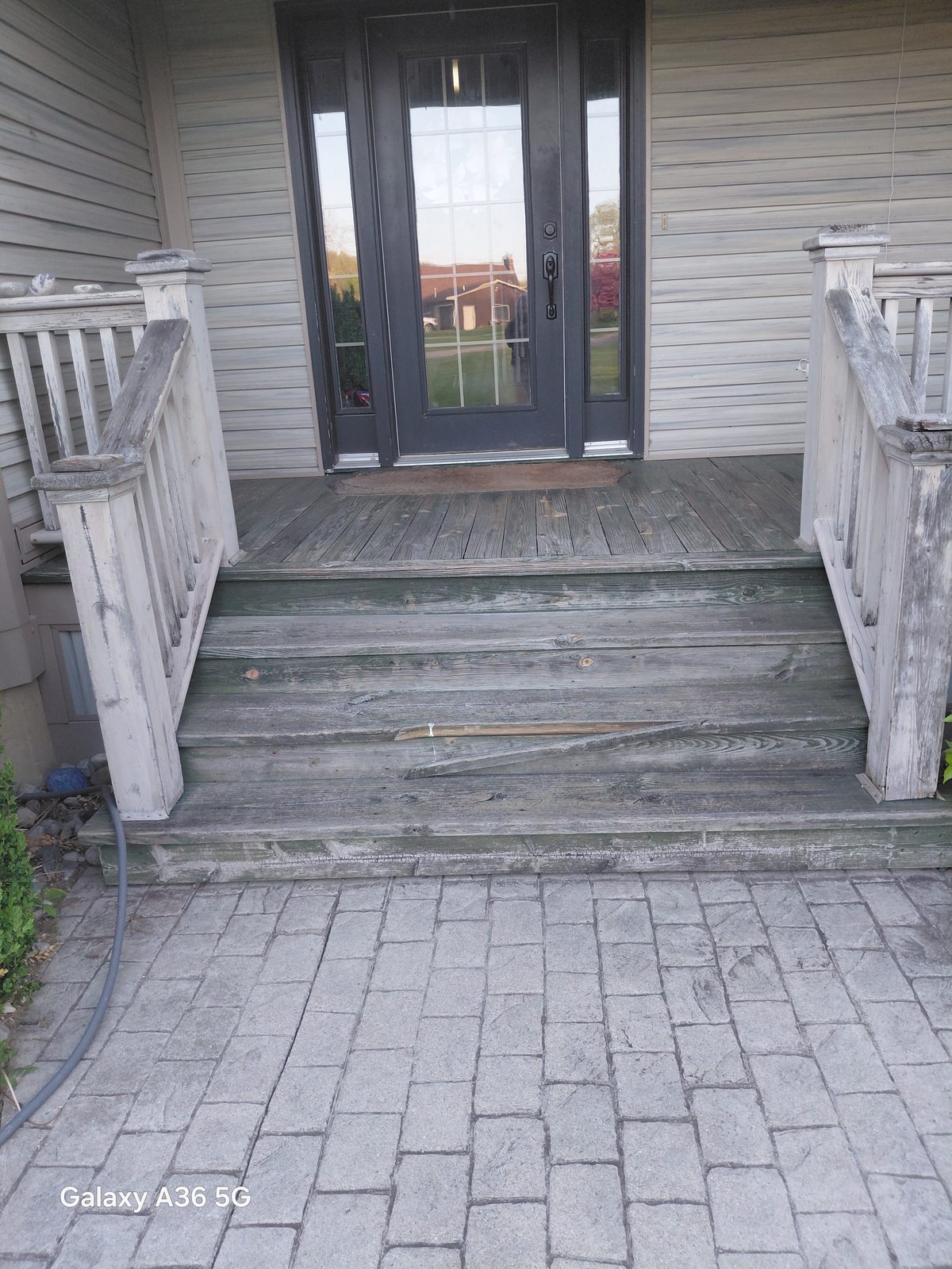 Front porch steps before repainting, showing weathered gray wood and a cracked tread